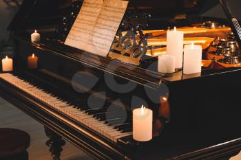 Stylish grand piano with burning candles in evening�