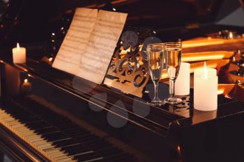 Stylish grand piano with burning candles and glasses of champagne in evening�