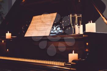 Stylish grand piano with burning candles and glasses of champagne in evening�