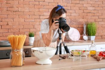 Young photographer taking picture of pasta in kitchen�