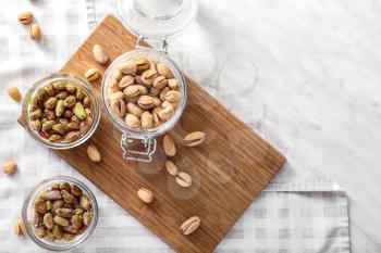 Bowls and jar with tasty pistachio nuts on table�