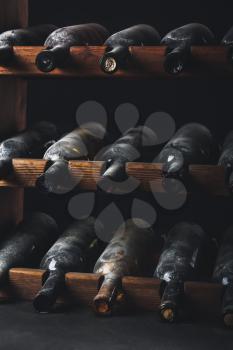 Wooden holder with bottles of wine in dark cellar�
