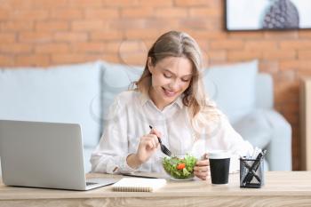 Woman eating healthy vegetable salad in office�