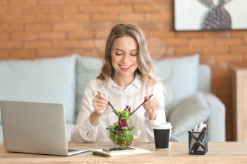 Woman eating healthy vegetable salad in office�