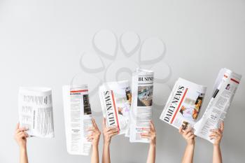 Female hands with newspapers on light background�
