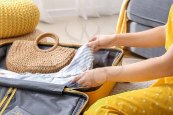 Young woman packing luggage at home�