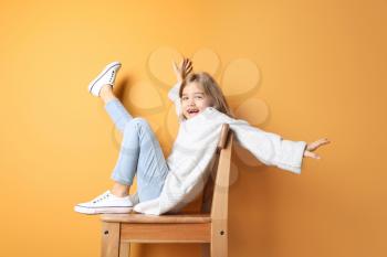 Happy fashionable girl sitting near color wall�