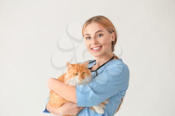 Female veterinarian with cute cat on white background�