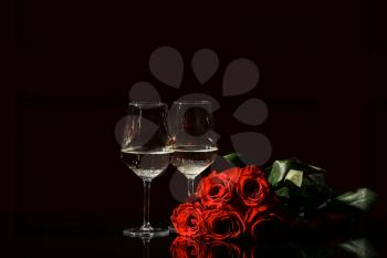 Glasses of champagne and rose flowers on dark background. Valentine's Day celebration�