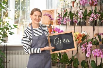 Florist holding chalkboard with text OPEN in shop�