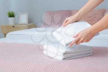 Woman putting clean towels on bed�