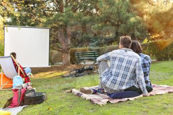 Young couple watching movie in outdoor cinema�