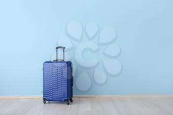 Packed suitcase near color wall. Travel concept�