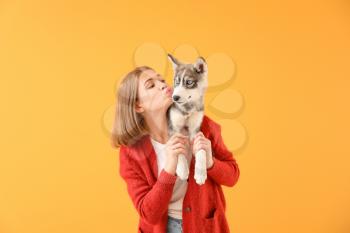 Cute teenage girl with funny husky puppy on color background�