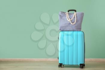 Suitcase and beach bag near color wall. Travel concept�