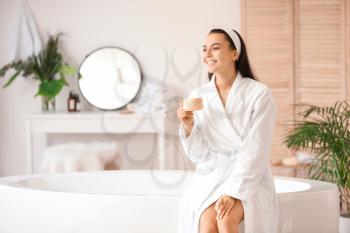 Beautiful young woman drinking coffee in bathroom�