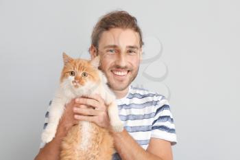 Man with cute cat on light background�
