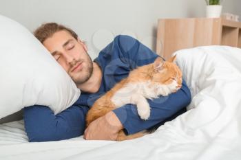 Morning of young man with cute cat sleeping in bed�
