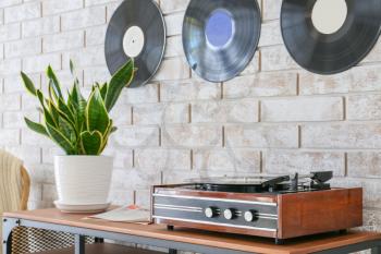 Record player with vinyl disc on table in room�