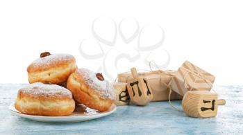 Donuts for Hanukkah, gifts and dreidels on table against white background�