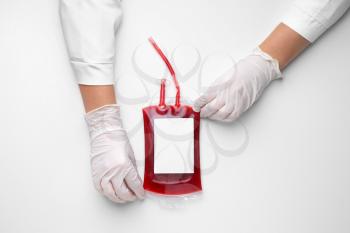 Hands of doctor with blood pack for transfusion on white background�