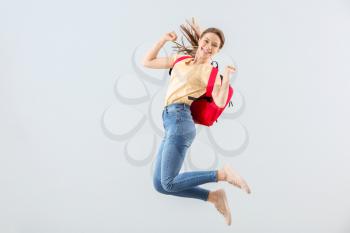 Jumping female student against light background 