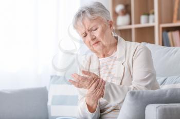 Senior woman suffering from pain in wrist at home�