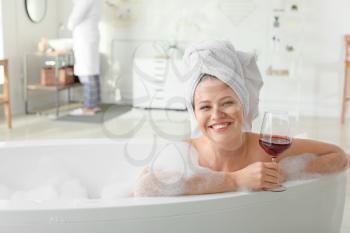 Beautiful young woman drinking wine while taking bath�