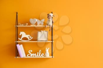Shelves with decor hanging on color wall�