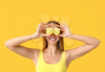 Beautiful young woman with lemons on color background�