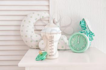 Bottle of milk for baby with pacifier on table indoors�