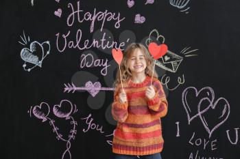Cute little girl with paper hearts near dark wall. Valentines Day celebration�