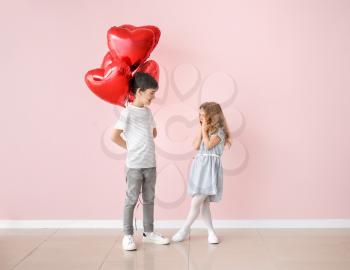 Little boy giving air balloons to cute girl on color background. Valentines Day celebration�