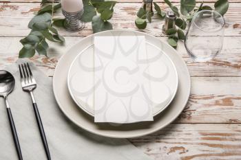 Beautiful table setting with empty menu on white wooden background�