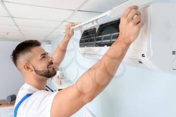 Male technician repairing air conditioner indoors�