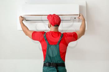 Male technician repairing air conditioner indoors�