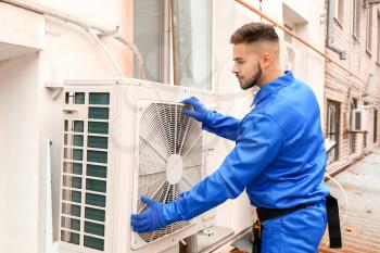 Male technician installing outdoor unit of air conditioner�
