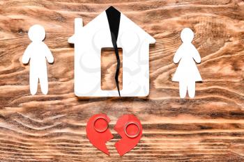 Human figures, house with crack, rings and broken heart on wooden background. Concept of divorce�