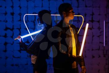 Young couple with neon lamps on dark color background�