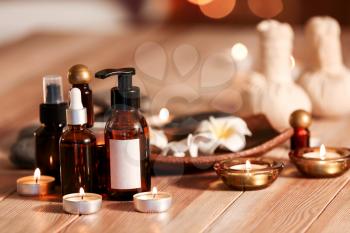 Bottles of essential oil and candles on table in spa salon�