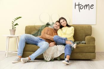 Young couple sitting on sofa at home�