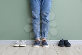 Young man with different stylish shoes near color wall�
