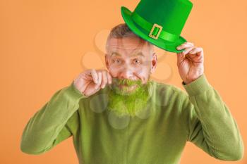 Funny mature man on color background. St. Patrick's Day celebration�