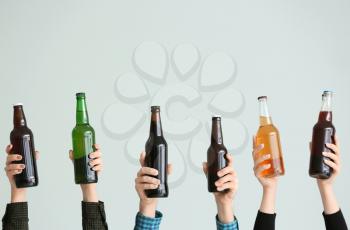 Hands with bottles of beer on grey background�