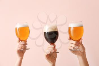 Hands with glasses of beer on color background�