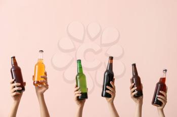 Hands with bottles of beer on color background�