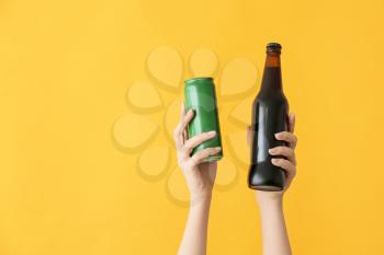 Hands with bottle and can of beer on color background�