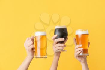 Hands with fresh beer on color background�