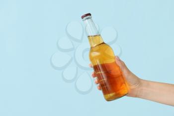Hand with bottle of beer on color background�