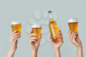 Hands with fresh beer on grey background�